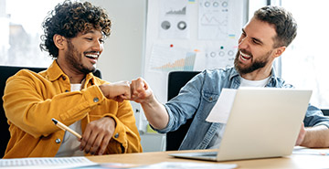 Two people in an office fist-bumping.